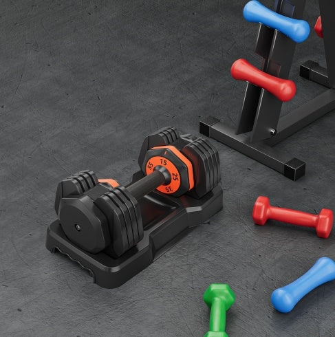 Set of adjustable dumbbells on a dark surface with additional colored dumbbells.